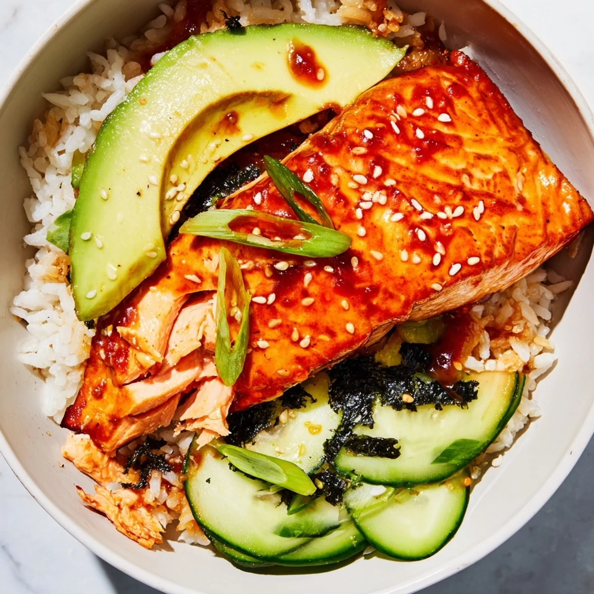 Vibrant Emily Mariko-Inspired Sticky Orange Gochujang Salmon Bowl, featuring fresh avocado and crispy nori.