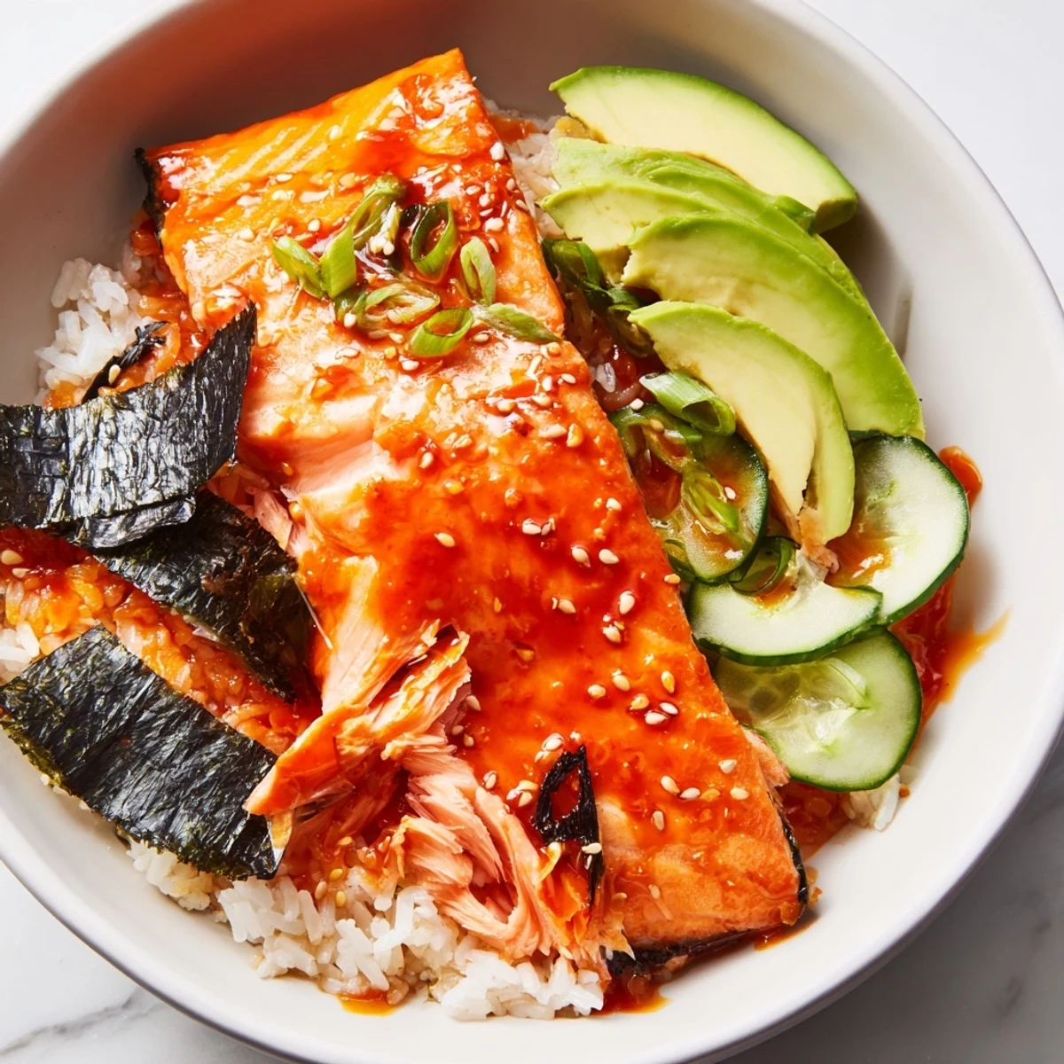 Emily Mariko-Inspired Sticky Orange Gochujang Salmon Bowl, with glazed salmon atop fluffy rice, awaits.
