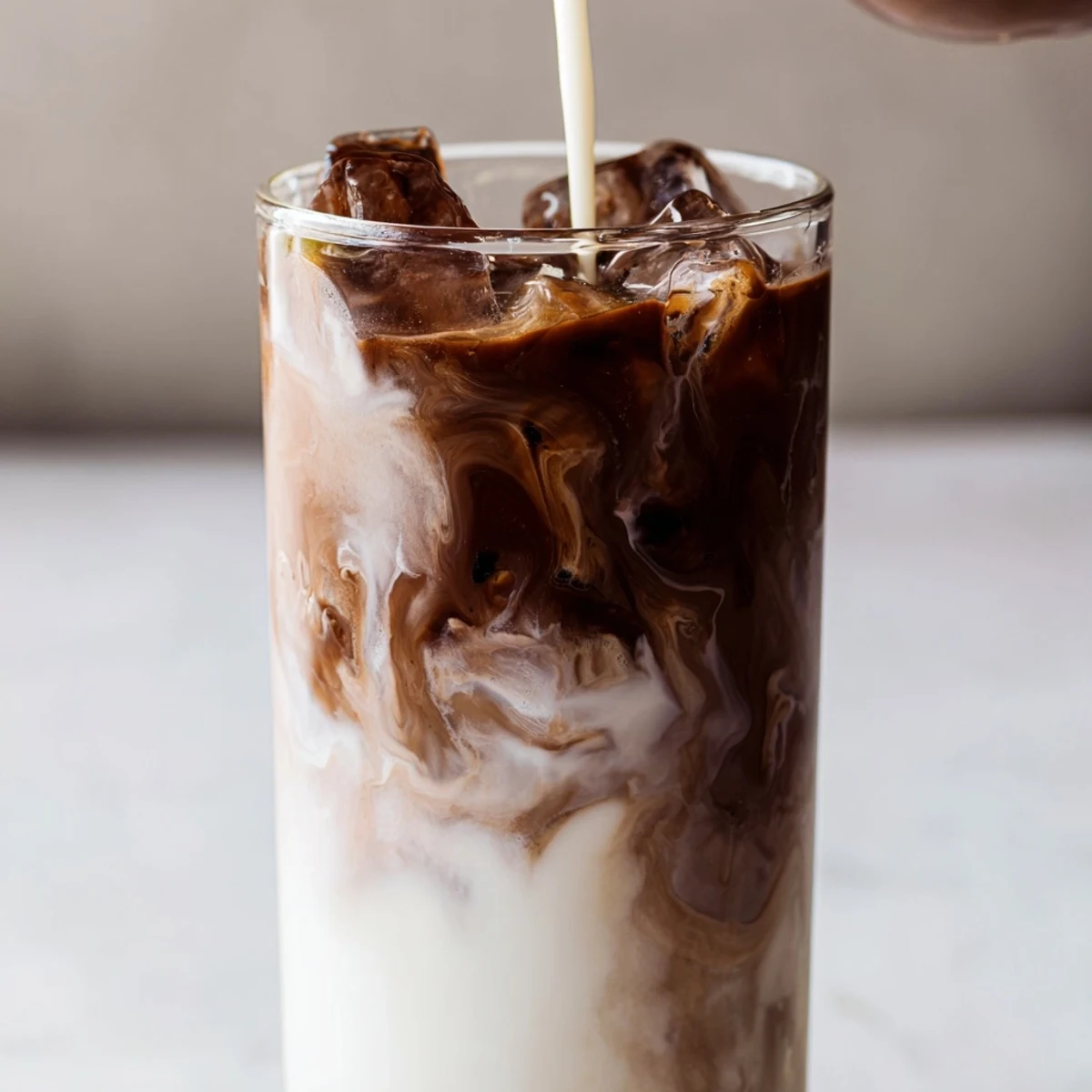 A hand holding a tall glass of the refreshing homemade Milo Ice Latte Hack, perfect for a quick afternoon energy boost.