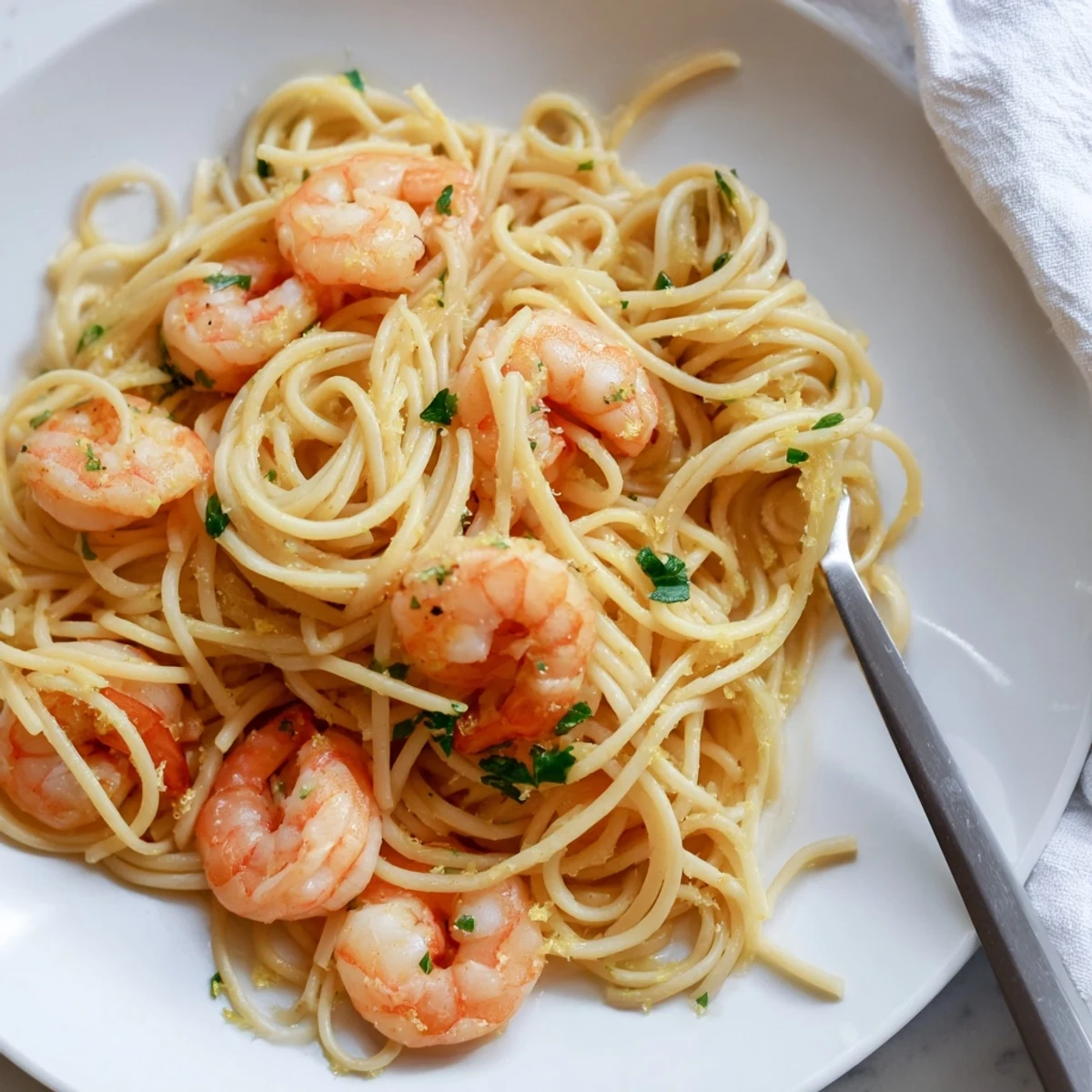 Freshly cooked Lemon Garlic Shrimp Pasta on a rustic plate, featuring plump pink shrimp and spaghetti in a glossy, golden lemon butter sauce.  