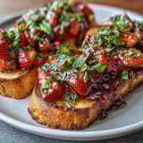 Fresh strawberry bruschetta with balsamic and mint served on golden toasted baguette slices for a vibrant summer appetizer.