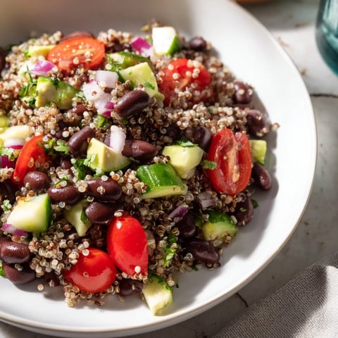 A colorful bowl of refreshing quinoa and black bean salad with creamy avocado slices.