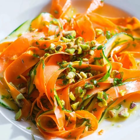Freshly tossed citrus carrot ribbon salad, featuring bright orange and yellow carrot ribbons with herbs.