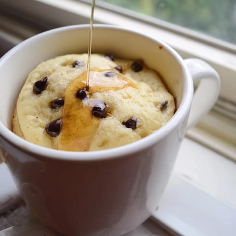Steaming hot Microwave Mug Pancake with melted chocolate chips, ready in under two minutes for a quick breakfast.  