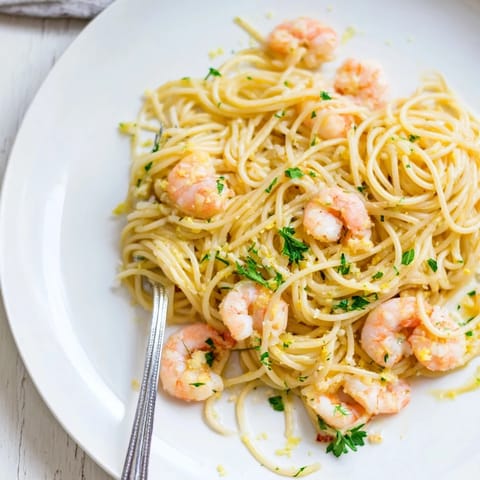 Steaming bowl of Lemon Garlic Shrimp Pasta garnished with chopped parsley and lemon wedges, ready for an easy weeknight Italian-American dinner.  