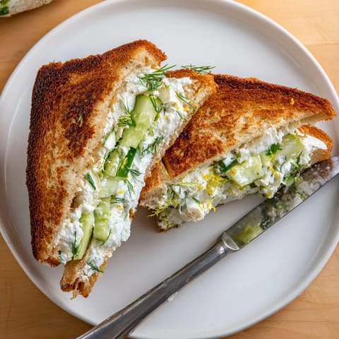 Fresh Whipped Feta Spring Grilled Cheese sandwiches on a plate, featuring melted cheese, vibrant dill, and thinly sliced cucumbers.  
