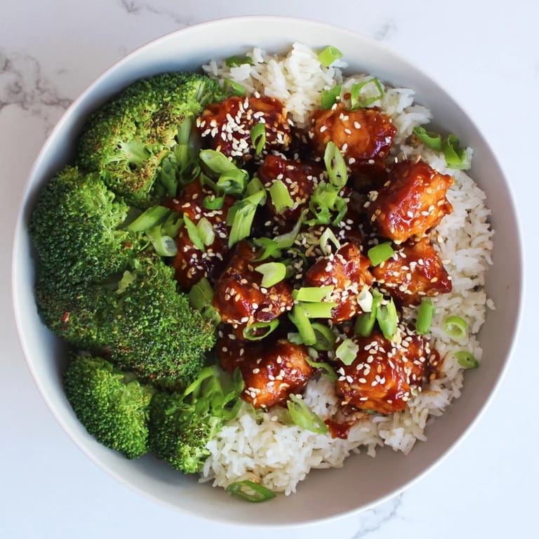 Homemade Sweet Chili Chicken Bowl with tender chicken, fluffy rice, and crisp broccoli, garnished with sesame seeds.