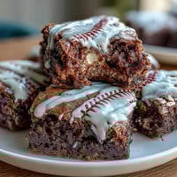 Baseball-themed brownie bites with white icing laces, perfect for game day celebrations.  