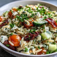 Bright summer orzo salad topped with crumbled feta and fresh lemon zest.